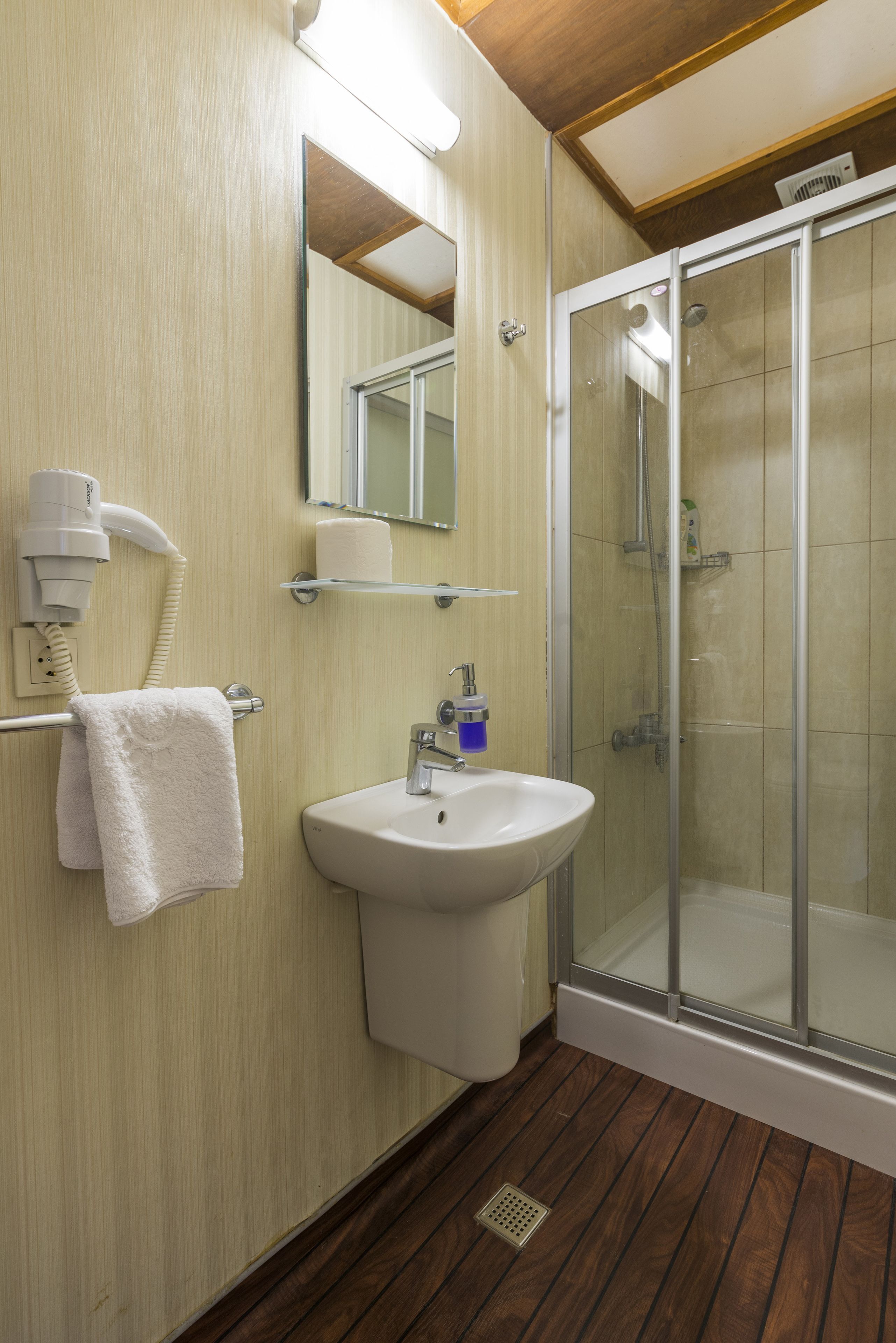 A bathroom with a sink, mirror, towel rack, and a glass-enclosed shower.