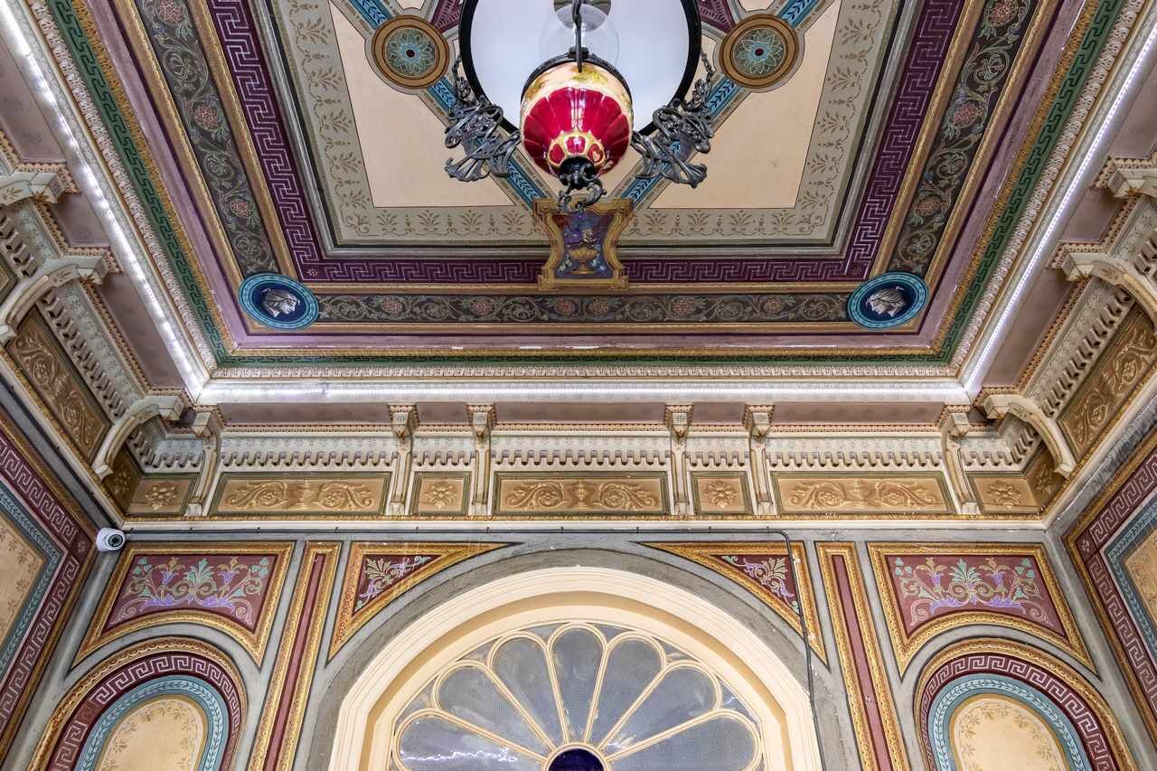 An ornate ceiling with intricate designs and a central chandelier.