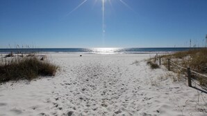 Una playa arenosa con cielo despejado y sol brillante.