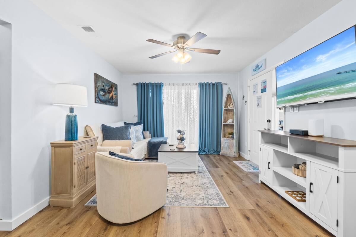 A living room with a sofa, a coffee table, a TV, and a ceiling fan.