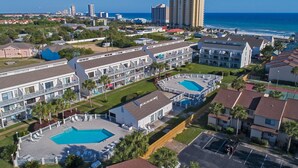 Un resort con varias construcciones, un área de piscina central y vista al océano.
