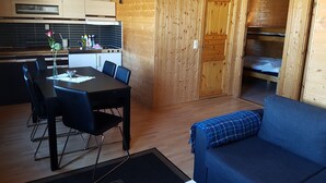 A compact, wooden cabin-style room with a dining area, kitchenette, and a cozy sleeping area. - Tjeldsundbrua Camping (Tjeldsund)