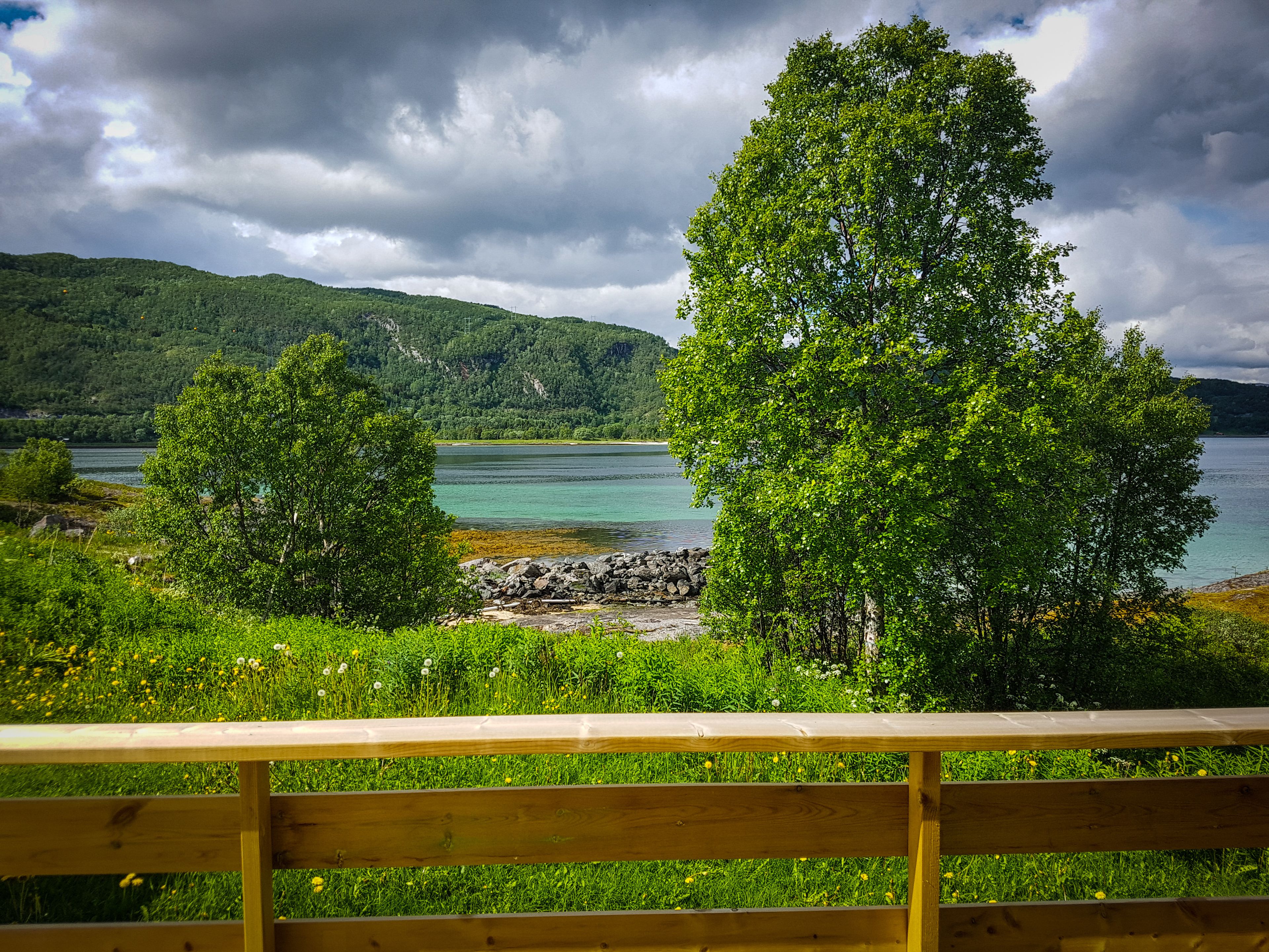A wooden bench overlooking a lake with trees and a distant mountain range.