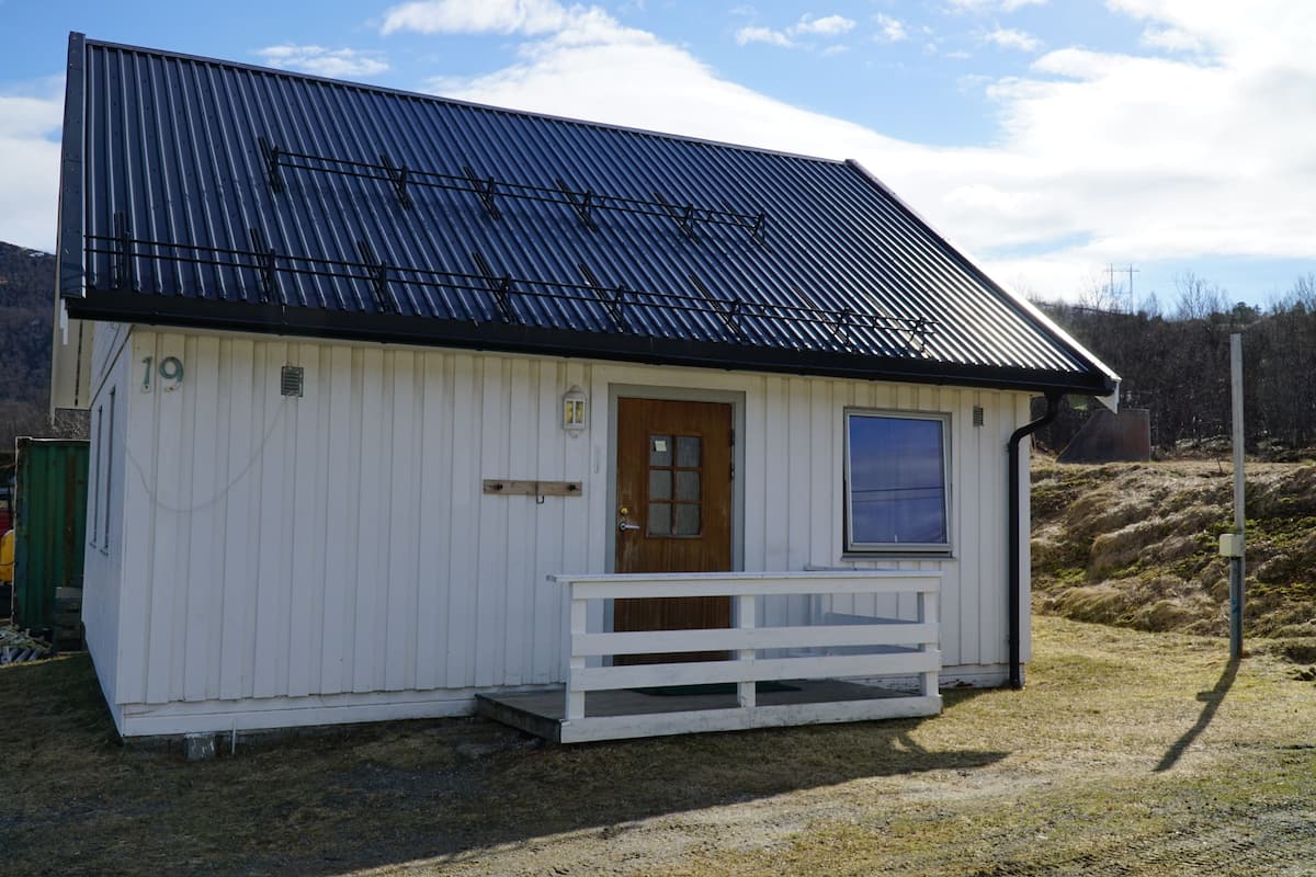 A small, single-story building with a metal roof, a wooden door, and a small window.