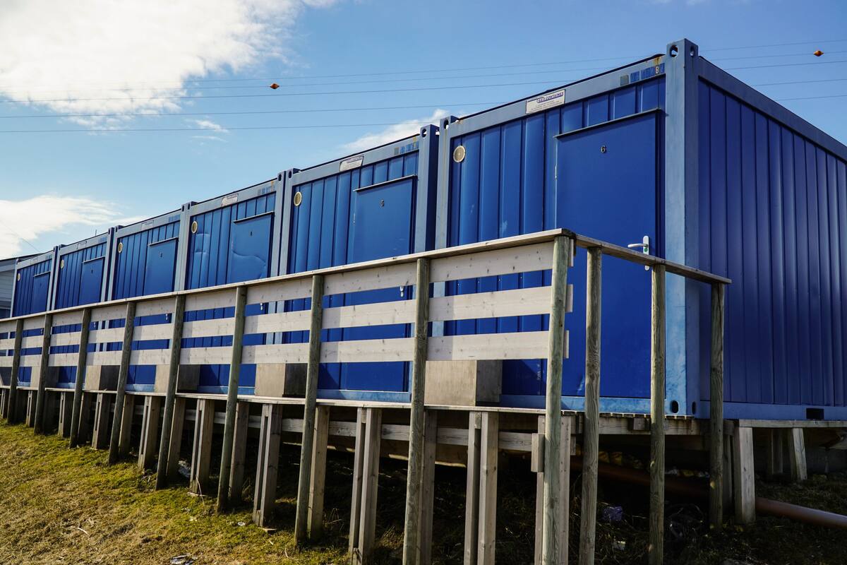 A series of blue shipping containers stacked on wooden supports.