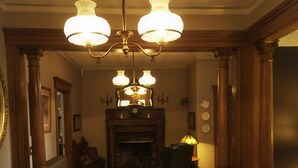 Una habitación cálidamente iluminada con suelo de madera, chimenea y candelabro.