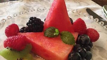 A plate of watermelon and assorted berries with a cup and glass in the background.