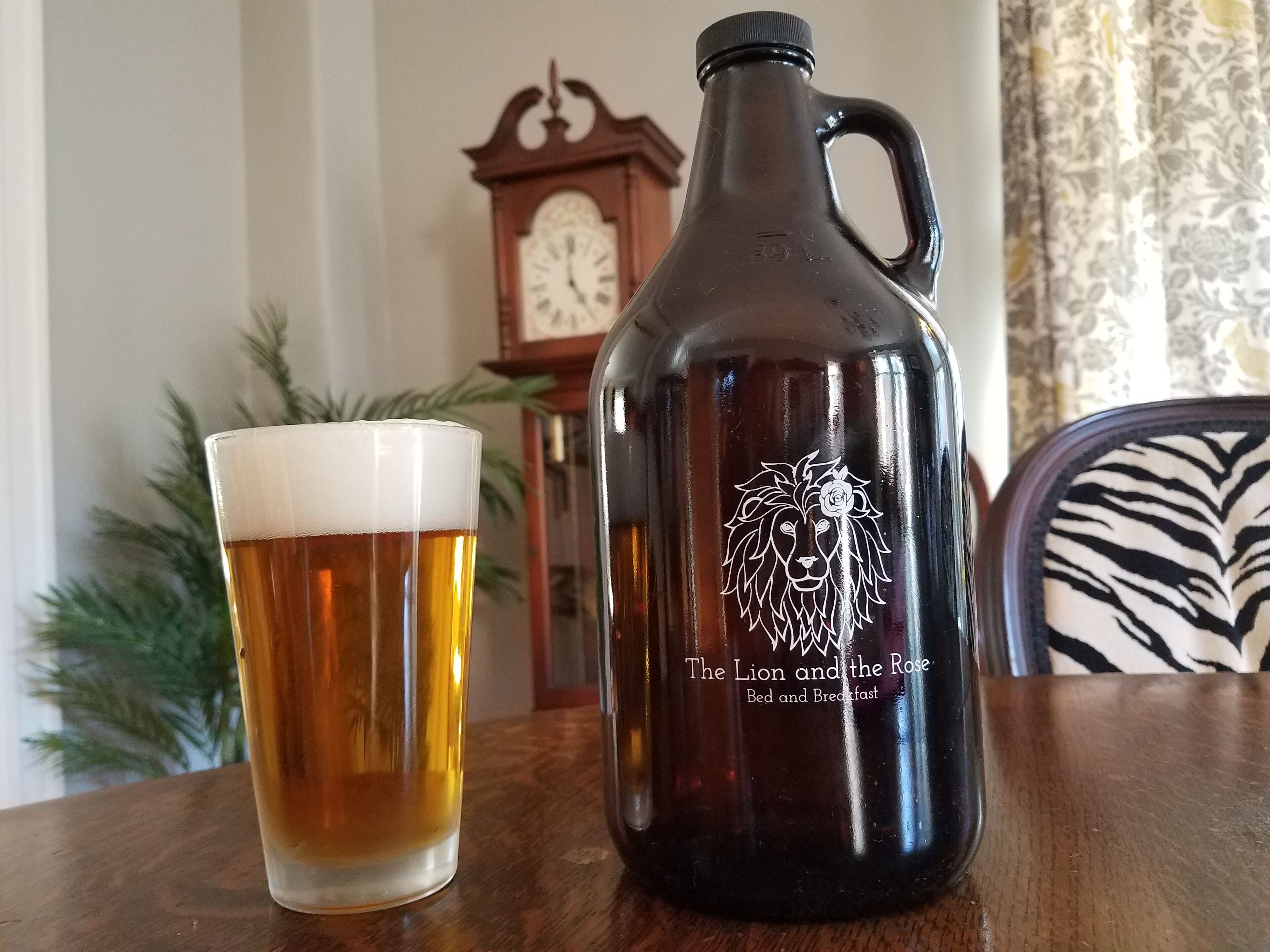 Un verre de bière et un pichet en métal orné d’un motif de lion, posés sur une table en bois.