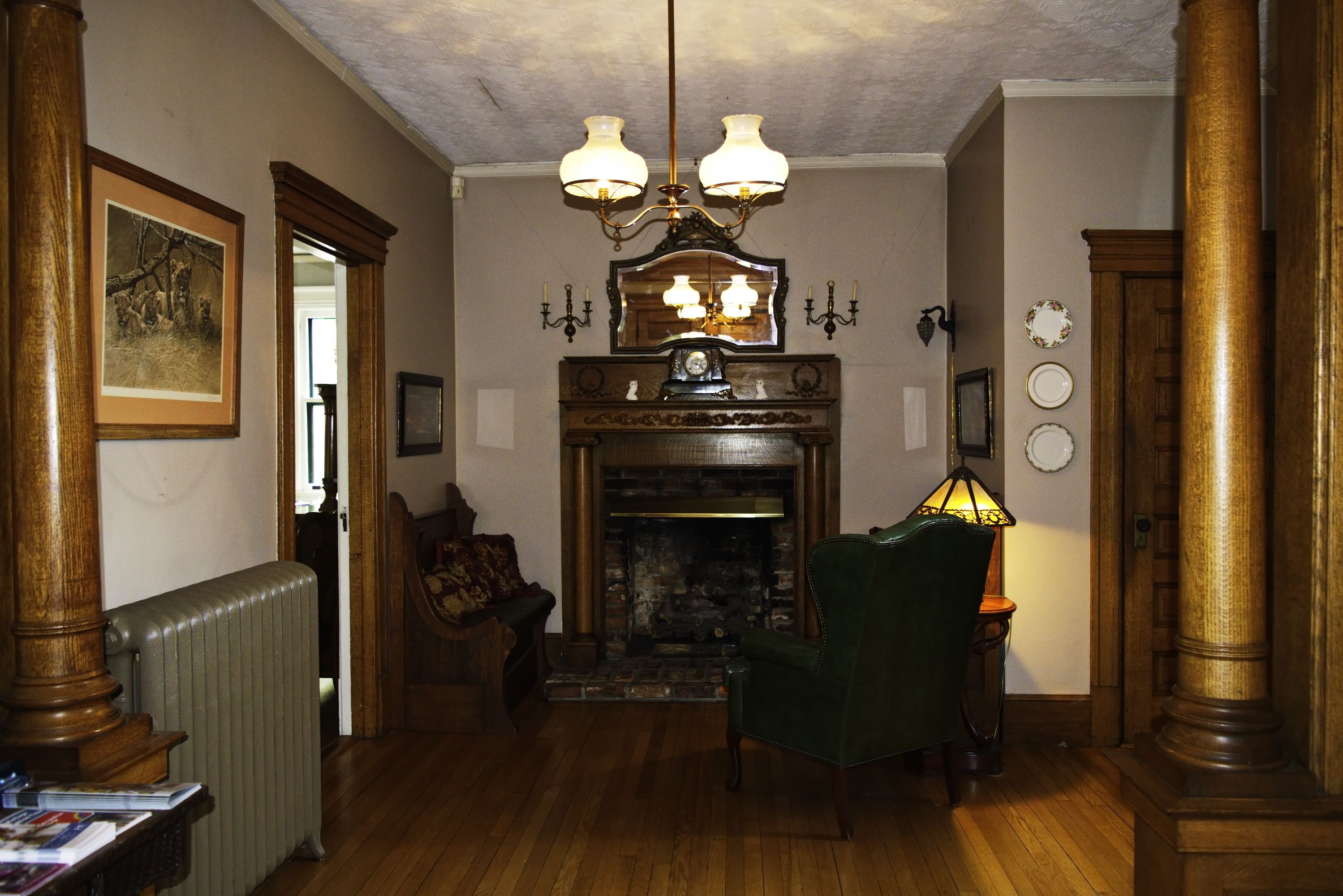 Ein traditionell eingerichteter Raum mit Kamin, Holzmöbeln und einem grünen Sessel.