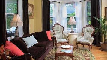 A cozy living room with a dark brown sofa, two armchairs, a small table, and a floral patterned rug.