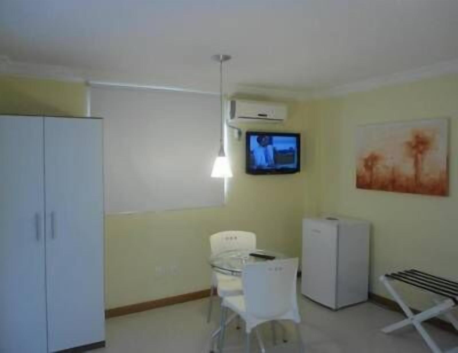 Una habitación pequeña y con pocos muebles, con una cama individual, un escritorio, una silla, un televisor y un radiador.