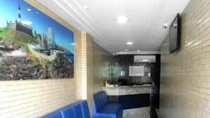 A reception area with a blue bench seating, a counter, and a mural on the wall. - Barra Mar Hotel (Salvador)