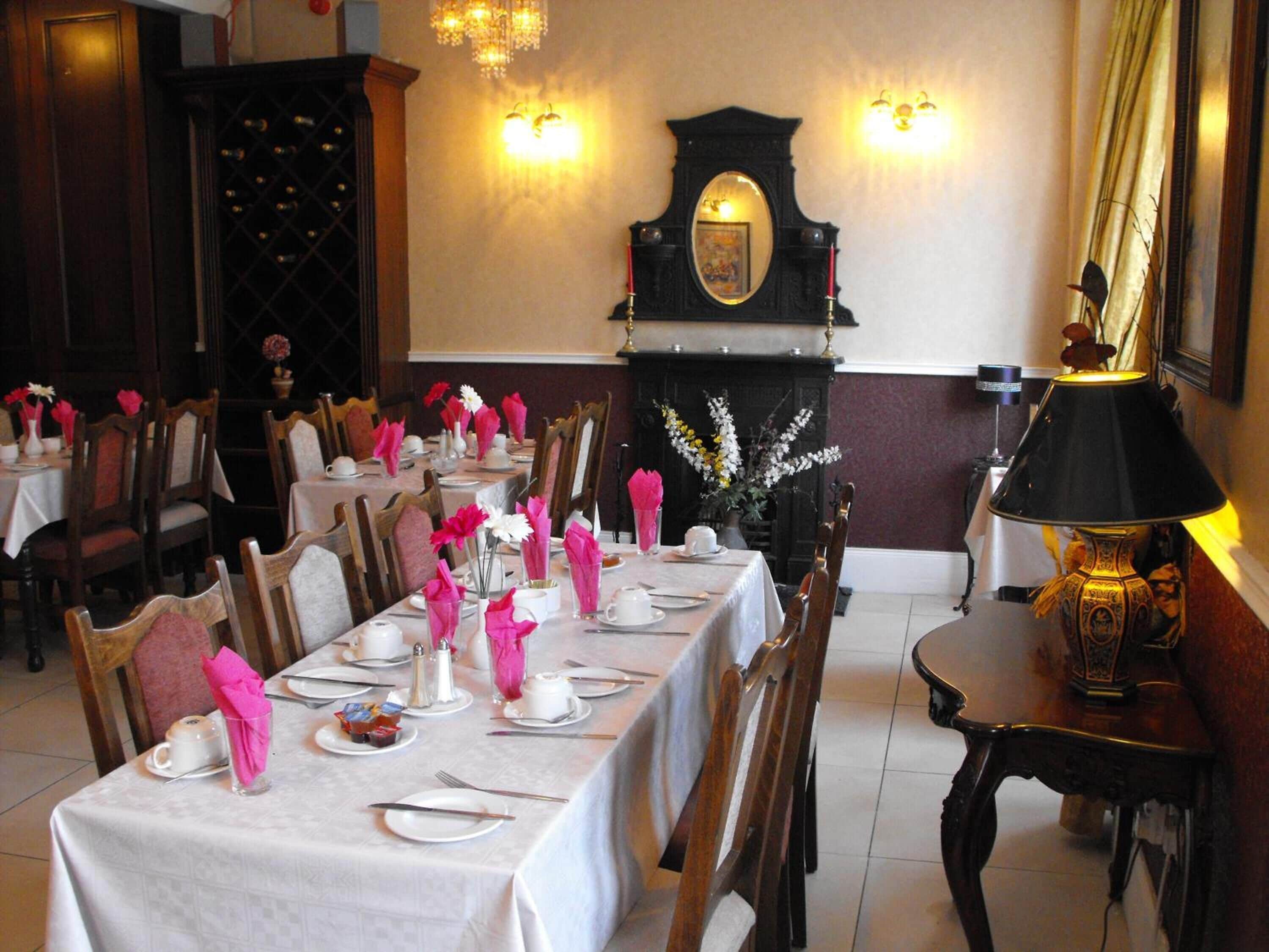 A dining area with tables set for service, a fireplace, and a chandelier.
