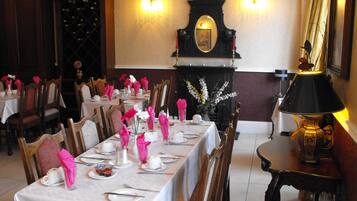 A dining area with tables set for service, a fireplace, and a chandelier.