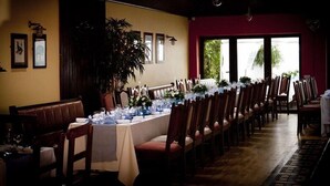 A long dining table set with chairs, a potted plant, and framed pictures on the wall. - Myles Creek Guesthouse (Kilkee)