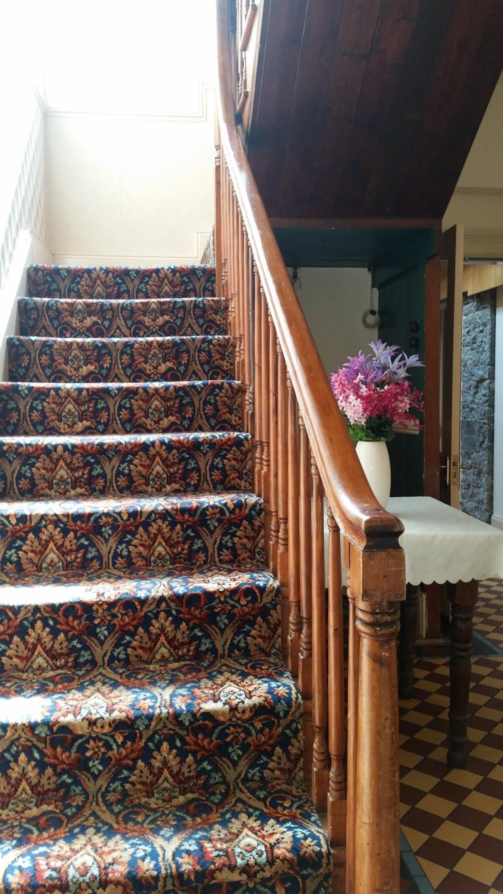 A staircase with ornate carpeted steps and wooden handrails.