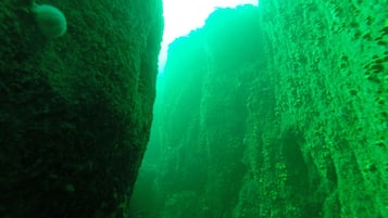 A narrow passageway with rough, textured walls and a bright light source at the end.