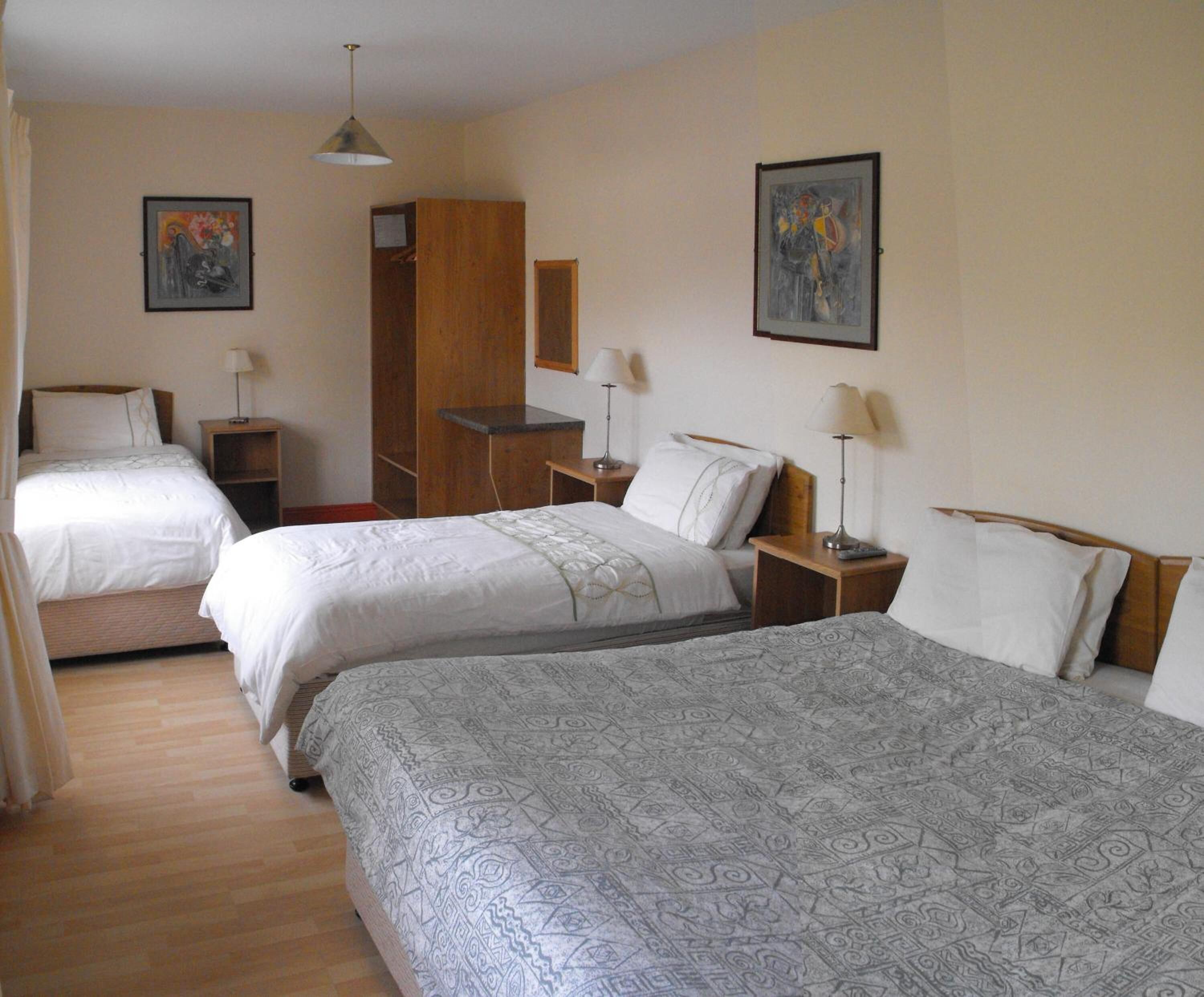 A hotel room with two beds, a wardrobe, a desk, and a chair.