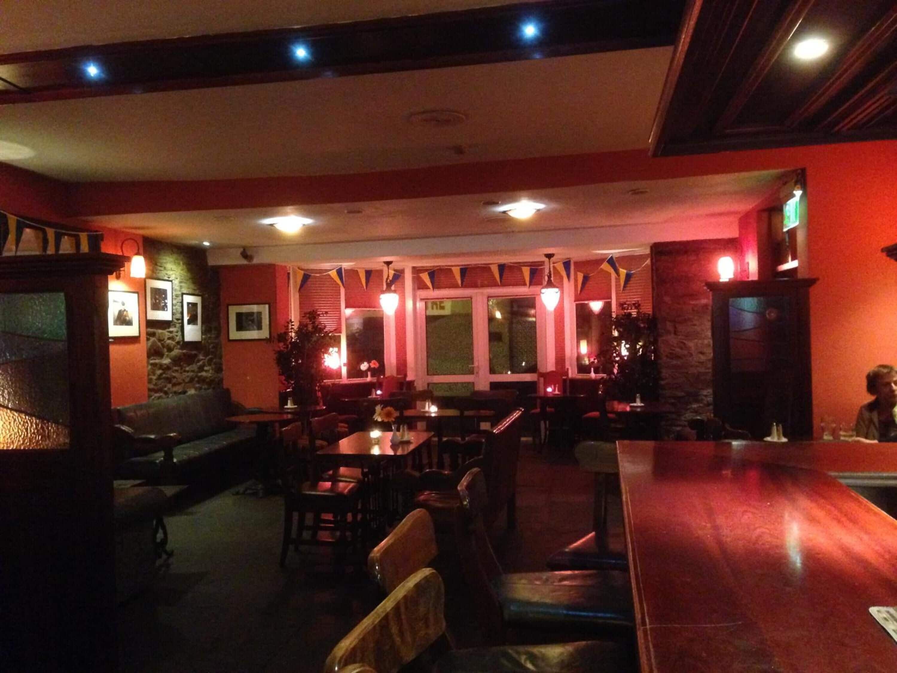 Un restaurant intérieur avec des meubles en bois, des murs en pierre et une décoration rouge.