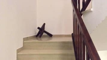 Een trap met een houten leuning en een witte muur.