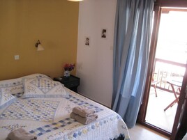 Un dormitorio con una cama grande, una mesita de noche, una lámpara de pared y vistas al exterior mediante una puerta corredera.
