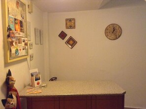 Una cocina con encimera, un reloj en la pared y varios objetos decorativos en la pared.