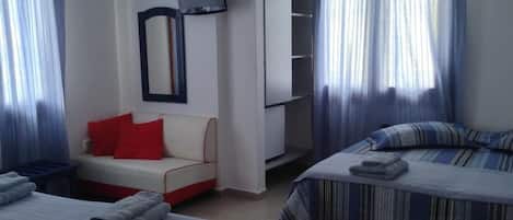 A hotel room with two beds, a sofa, a TV, and a wardrobe.