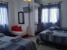 A hotel room with two beds, a sofa, a TV, and a wardrobe.