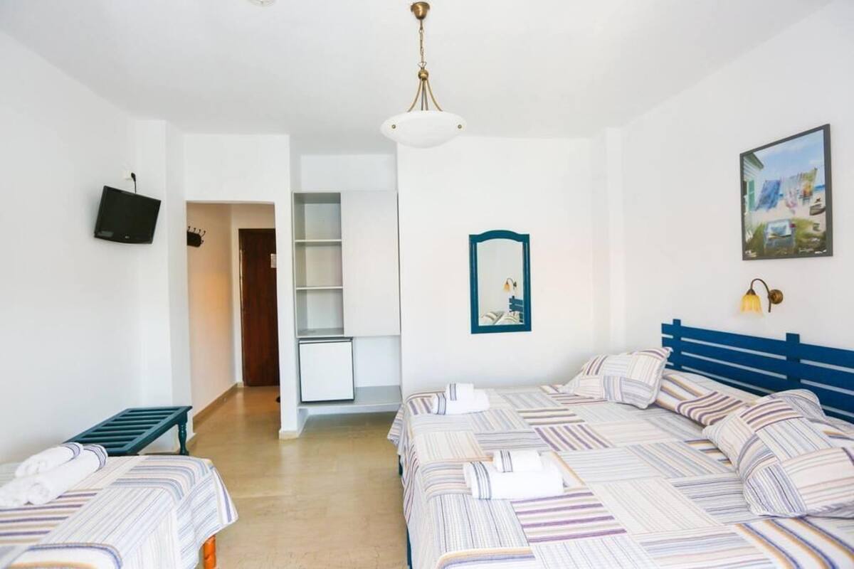 Habitación de hotel con una cama grande, un escritorio pequeño, televisión y un cuadro en la pared.