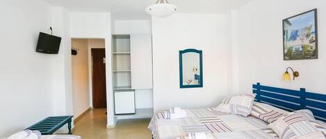 A hotel room with a large bed, a small desk, a television, and a painting on the wall.