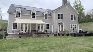 A two-story house with a covered patio, a chimney, and a garage. - The Old Lantern Inn and Barn (Charlotte)