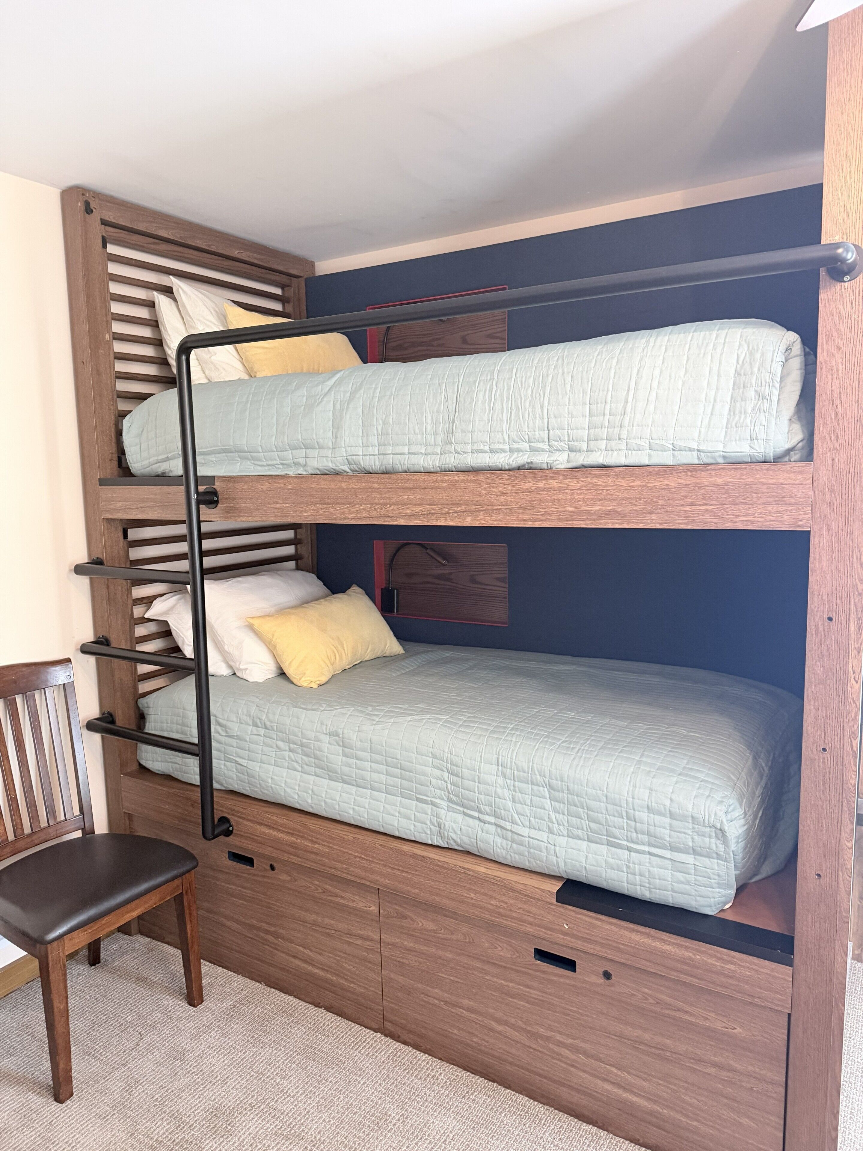 A bunk bed with a wooden frame, two beds, and a chair.