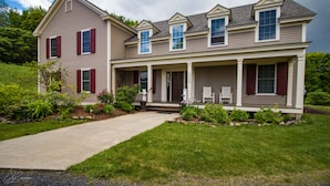 A two-story house with a front porch, a covered entryway, and a driveway. - The Old Lantern Inn and Barn (Charlotte)