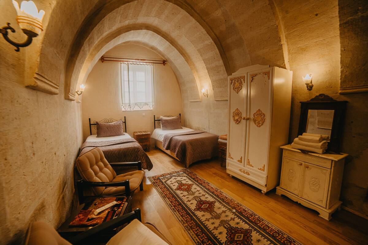 A bedroom with two beds, a wardrobe, a mirror, and a rug.