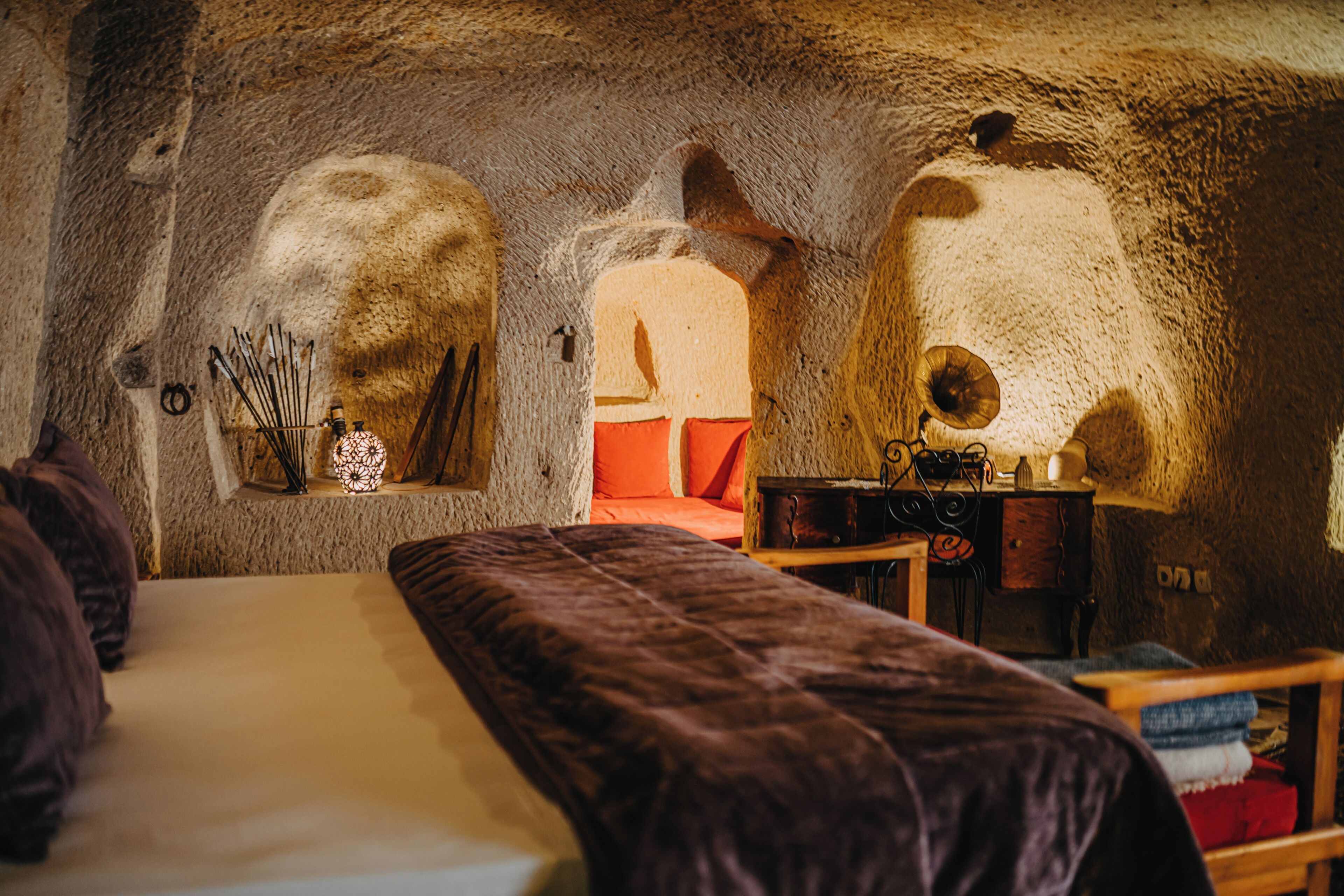A room with a bed, a wooden table, and a stone wall.