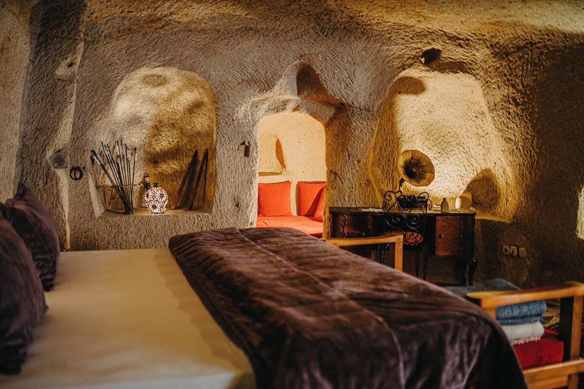 A room with a bed, a wooden table, and a stone wall.