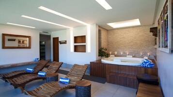 Een moderne spa-ruimte met houten ligbedden, een jacuzzi en een stenen muur.