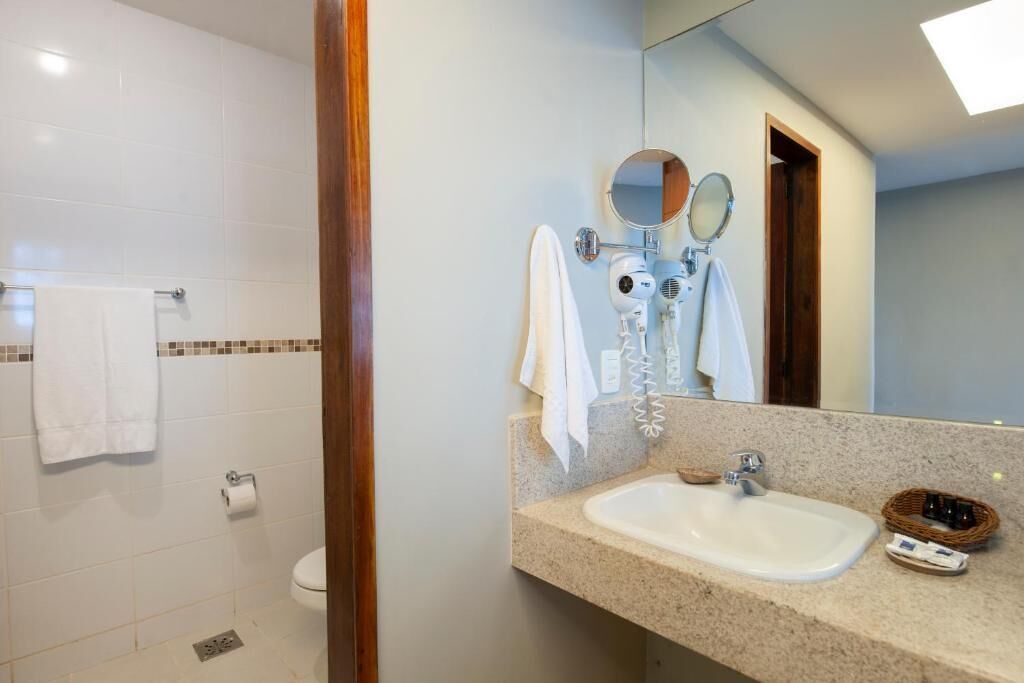 Een badkamer met een wastafel, twee spiegels, een handdoekrek en een toilet.