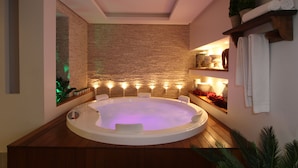 Een moderne badkamer met een vrijstaand ligbad, houten vloeren, een accentmuur van baksteen, en een plank met handdoeken en planten.