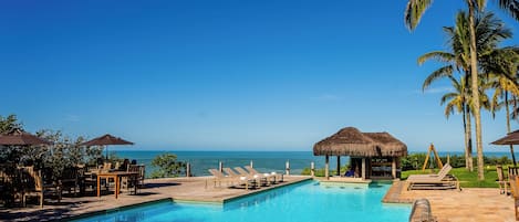 Una piscina al aire libre, sombrillas, sillones reclinables de piscina