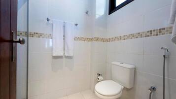 A small, clean bathroom with a toilet, a shower, and a glass door.