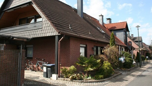 A row of brick houses with pitched roofs and a clear sky. - Messezimmer4u (Düsseldorf)