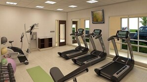 Un gimnasio con cintas de correr, una bicicleta estática y una máquina de remo.