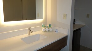 Un baño moderno con un lavabo blanco, un espejo grande y un perchero con artículos de aseo.