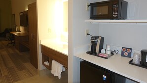 Habitación de hotel con kitchenette, que incluye microondas, cafetera y refrigerador pequeño.