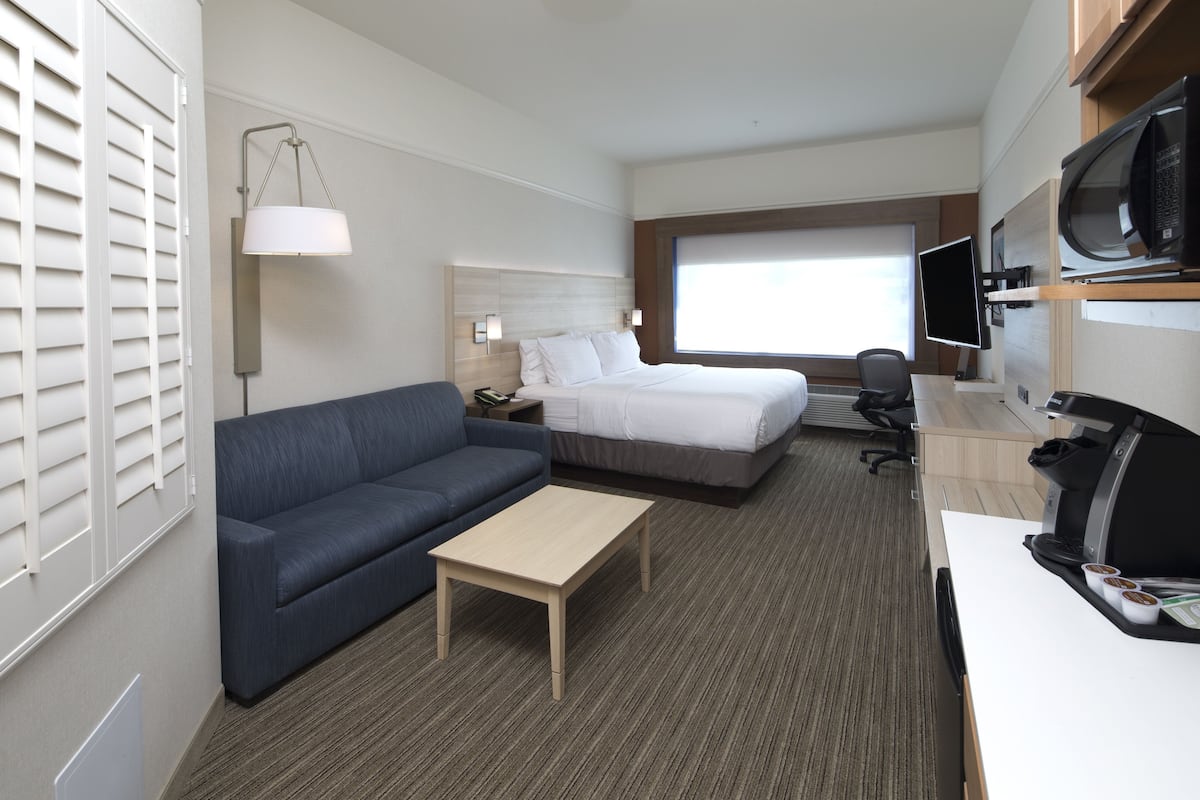 Ein Hotelzimmer mit Bett, Sofa, Schreibtisch, Fernseher und Mikrowelle.