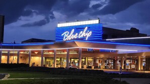 A hotel with a prominent 'Blue Chip' sign, outdoor seating area, and a parking lot. - Holiday Inn Express & Suites La Porte by IHG (La Porte)