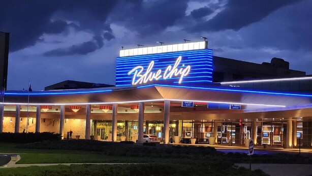A hotel with a prominent 'Blue Chip' sign, outdoor seating area, and a parking lot. - Holiday Inn Express & Suites La Porte by IHG (La Porte)