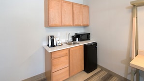 A compact kitchen with wooden cabinets, a black microwave, a coffee maker, and a dishwasher. - Holiday Inn Express & Suites La Porte by IHG (La Porte)