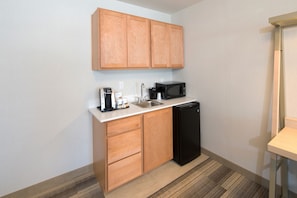 A compact kitchen with wooden cabinets, a black microwave, a coffee maker, and a dishwasher. - Holiday Inn Express & Suites La Porte by IHG (La Porte)